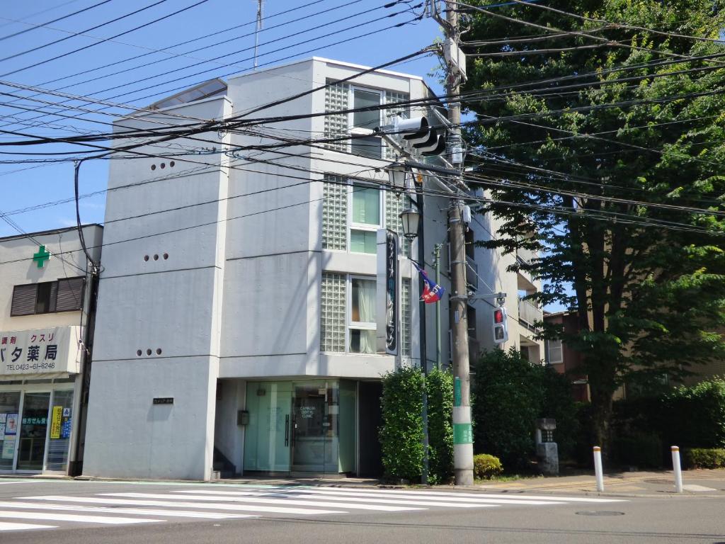 biały budynek na rogu ulicy w obiekcie カメリア府中202号室 w mieście Fuchū