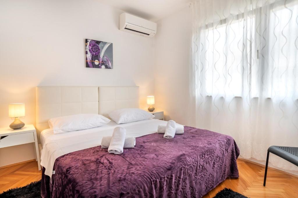 a bedroom with a large bed with a purple blanket at Rooms&Apartments Zelux in Split