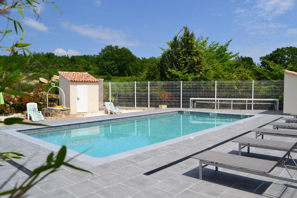 a swimming pool with two chairs and a fence at Village de gîtes Les Olivettes in Saint-Dézéry