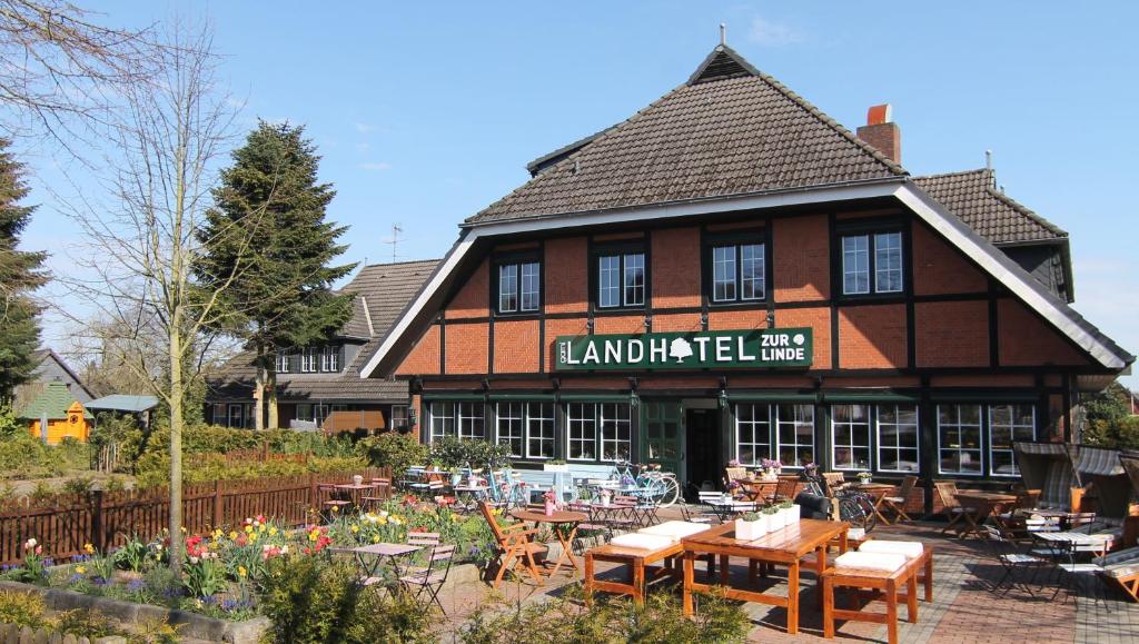 a building with tables and chairs in front of it at Landhotel garni zur Linde in Ratekau