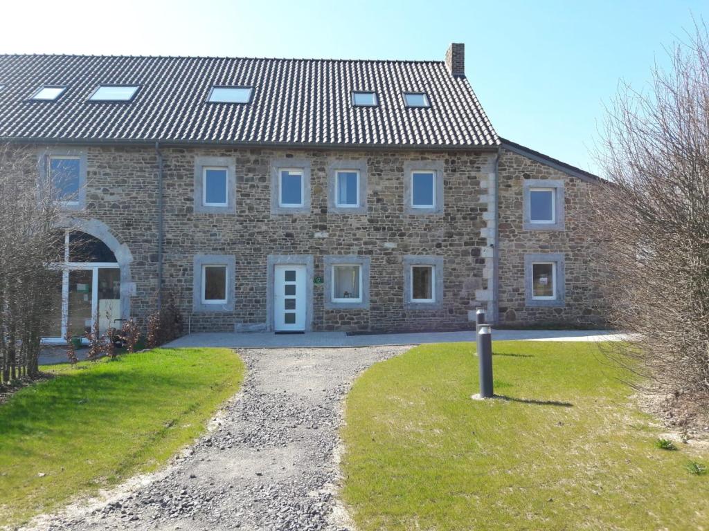 ein Backsteinhaus mit blauen Fenstern und einer Auffahrt in der Unterkunft Gîte des Ayrifagnes in Theux