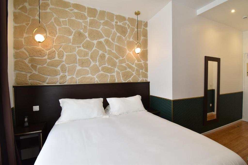 a bedroom with a white bed and a stone wall at Hôtel Bonne Nouvelle in Paris
