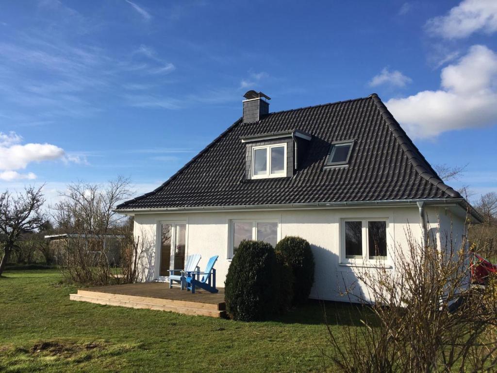 a white house with a table and a blue chair at Nordseeblick Ferienhaus in Wobbenbüll