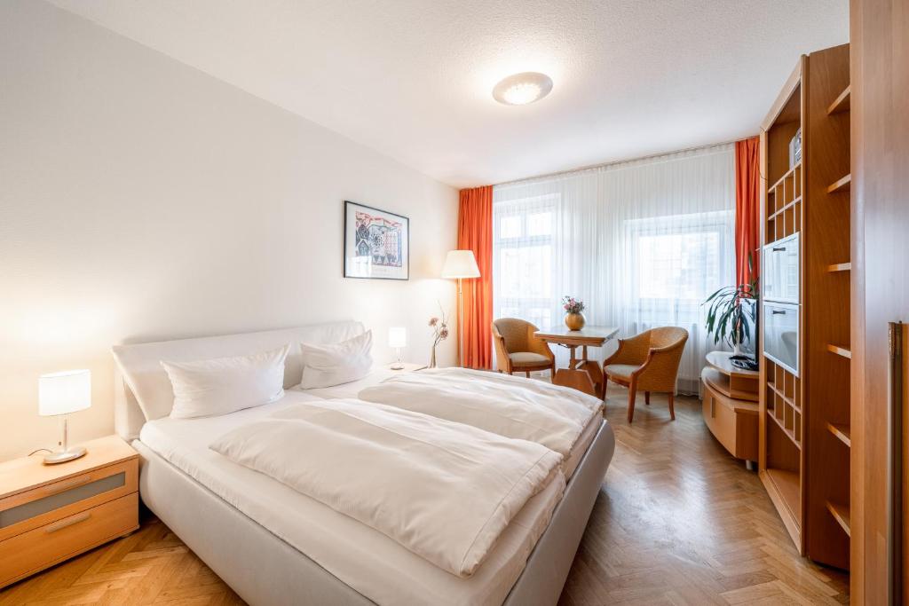 ein Schlafzimmer mit einem großen weißen Bett und einem Tisch in der Unterkunft Aparthotel Münzgasse An der Frauenkirche in Dresden