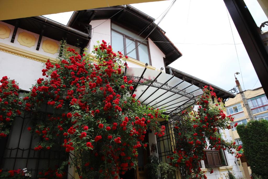 a building with red flowers on the side of it at Pension Kokett in Câmpulung