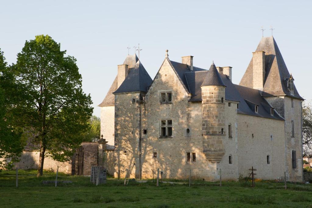 een oud kasteel in een veld met een boom bij Château de Bois Charmant in Les Nouillers