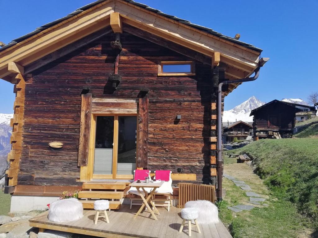 a log cabin with chairs and a table at forno one in Bürchen