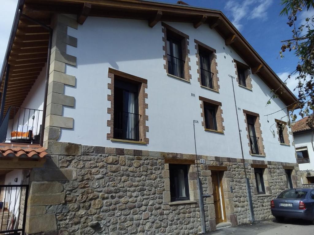 un edificio blanco con ventanas y pared de piedra en La Casa de la Bolera, en Periedo