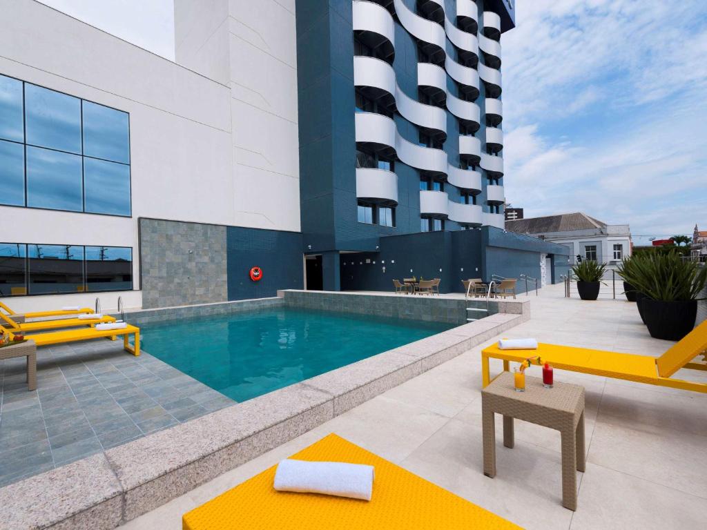 uma piscina com mobiliário amarelo e um edifício em Novotel Itajai em Itajaí