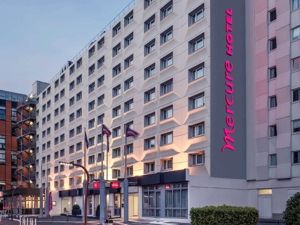 ein großes weißes Gebäude mit einem rosa Schild drauf in der Unterkunft Mercure Paris Porte d'Orleans in Montrouge