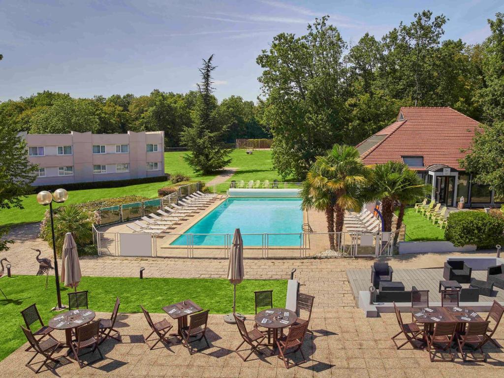 尤里的住宿－楓丹白露尤里諾富特酒店，一个带桌椅的户外庭院和一个游泳池