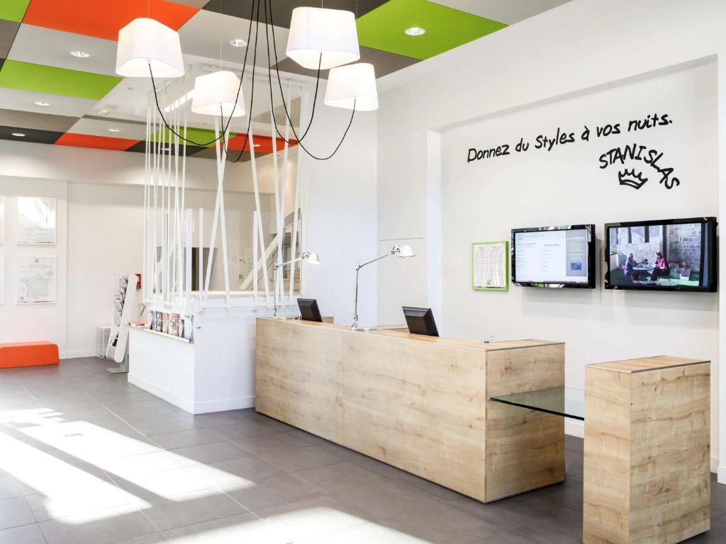 an office with a reception desk and a sign on the wall at ibis Styles Nancy Sud in Houdemont