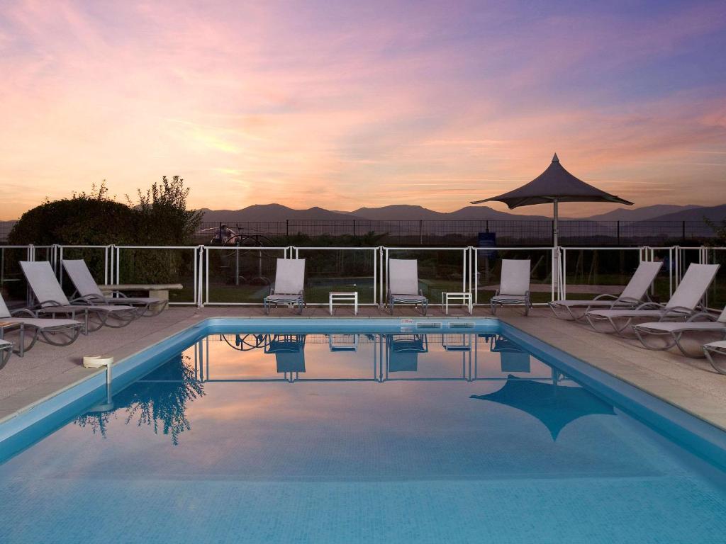 科爾馬的住宿－科爾馬北宜必思尚品酒店，一个带椅子和遮阳伞的游泳池
