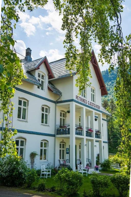 un gran edificio blanco con sillas delante en Petrines Gjestgiveri, en Norddal