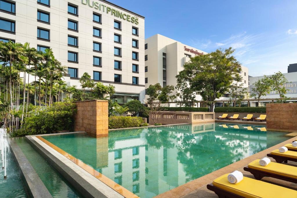 una foto di una piscina dell'hotel con sedie a sdraio di Dusit Princess Srinakarin Bangkok a Bangkok