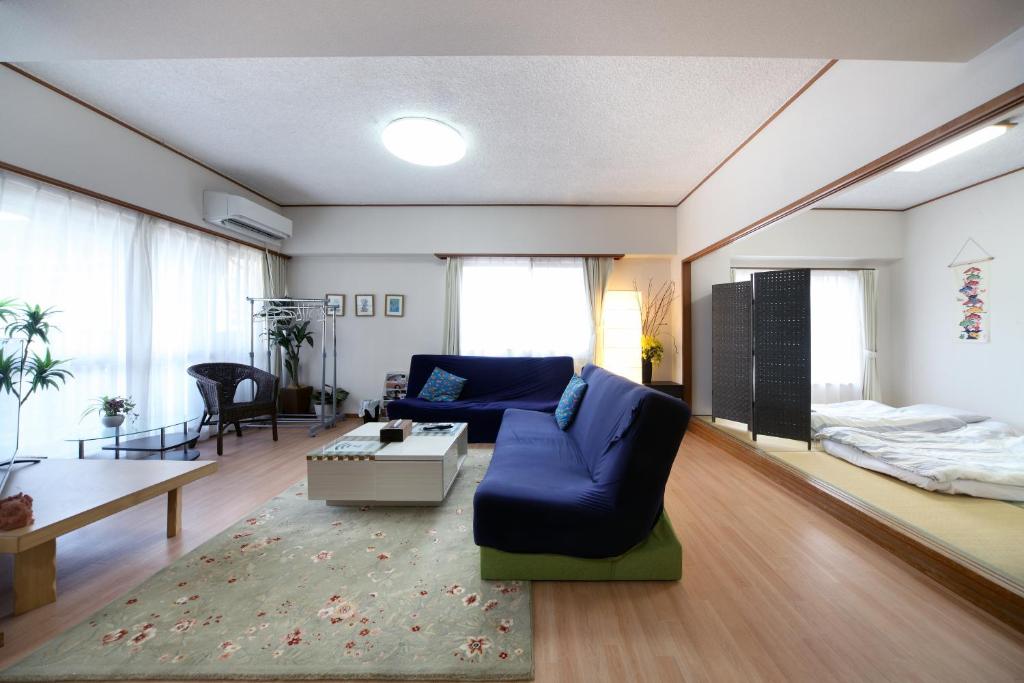 a living room with a blue couch and a table at Exsaison house Kumoji in Naha