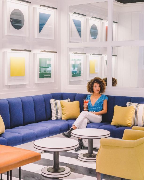 a woman sitting on a blue couch in a room with tables at Seventy Barcelona in Barcelona