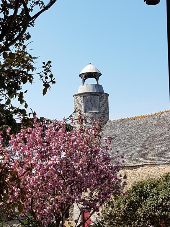 einen Leuchtturm auf einem Gebäude mit einem blühenden Baum in der Unterkunft Les Cottages du Château du Rozel in Le Rozel