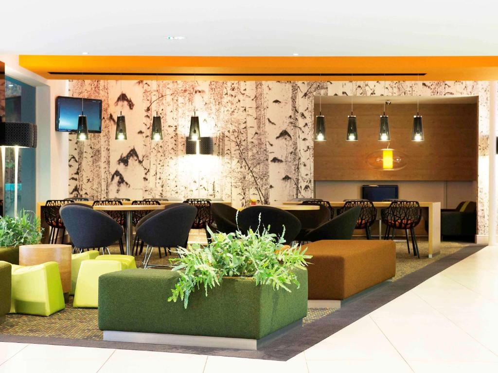 a lobby with a restaurant with tables and chairs at Novotel Rotterdam - Schiedam in Schiedam