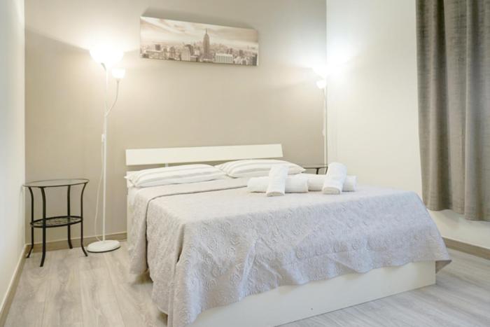 Dormitorio blanco con cama y lámpara en Affittacamere Romina, en Bolonia