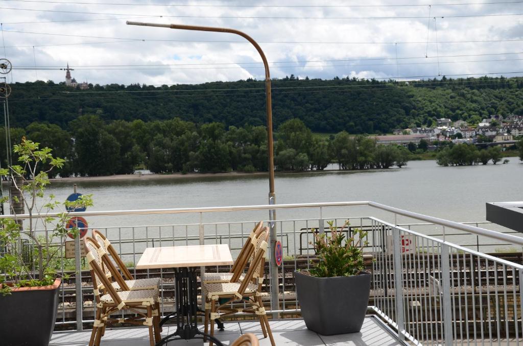 uma mesa e cadeiras numa varanda com vista para um rio em Hotel Rheinstein em Rüdesheim am Rhein