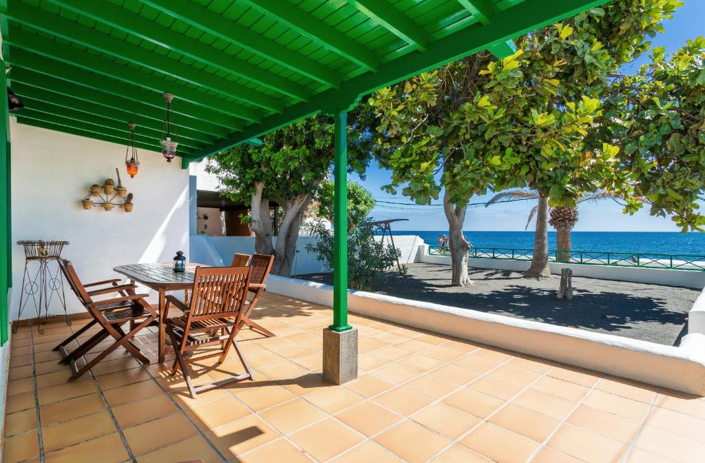 een patio met een tafel en stoelen en uitzicht op de oceaan bij Casajardin in Playa Honda