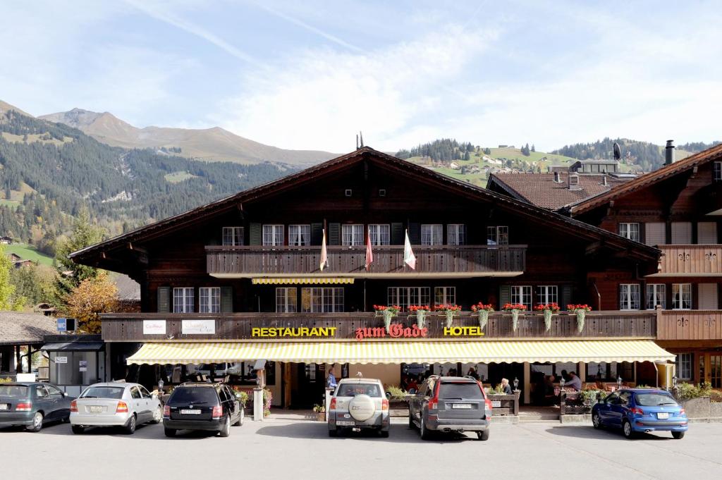 un gran edificio con coches estacionados frente a él en Hotel-Restaurant zum Gade, en Lenk