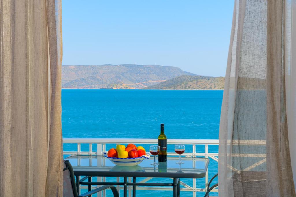 un tavolo con un cesto di frutta e una bottiglia di vino di Margarita's Seafront Luxury Apartment a Eloúnda