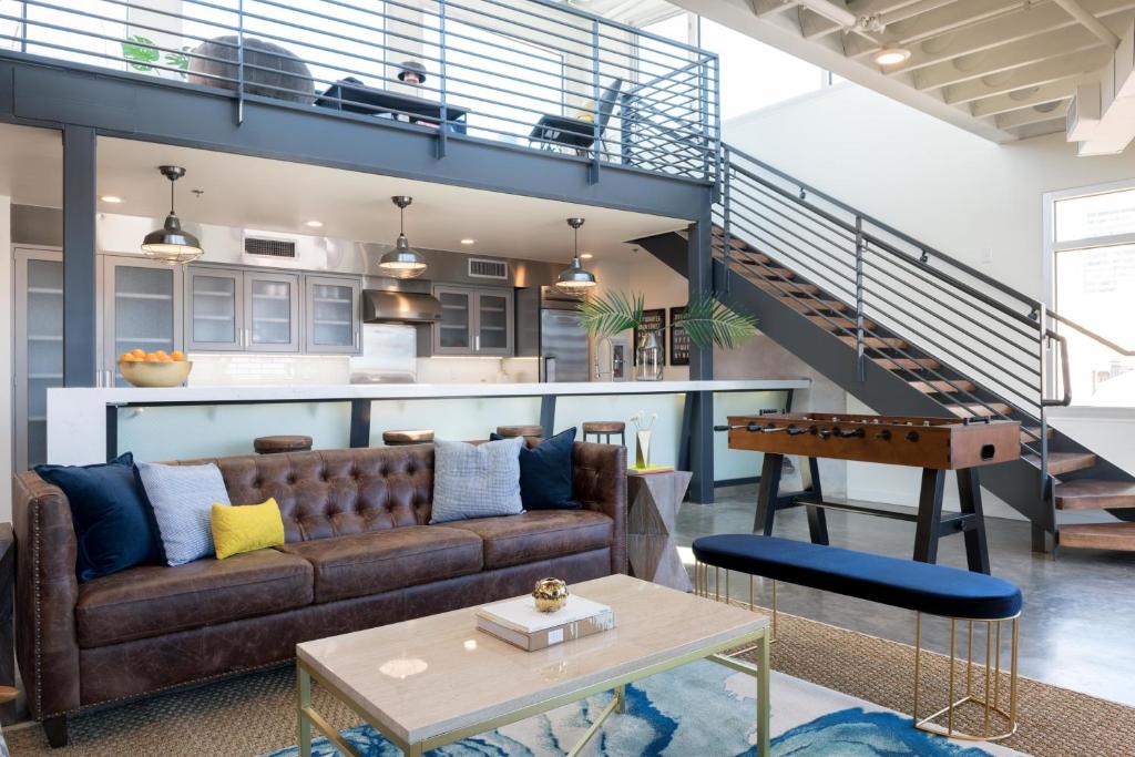 a living room with a brown couch and a staircase at Luxury Arts District Apartments in New Orleans