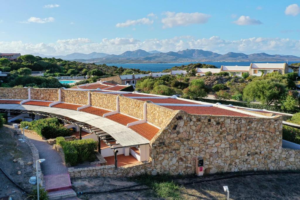 an external view of a building with a stone wall at Capo Ceraso Family Resort in Costa Corallina