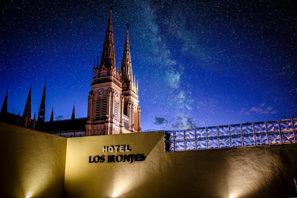 un gran edificio con una torre de reloj por la noche en Los Monjes Hotel en Luján