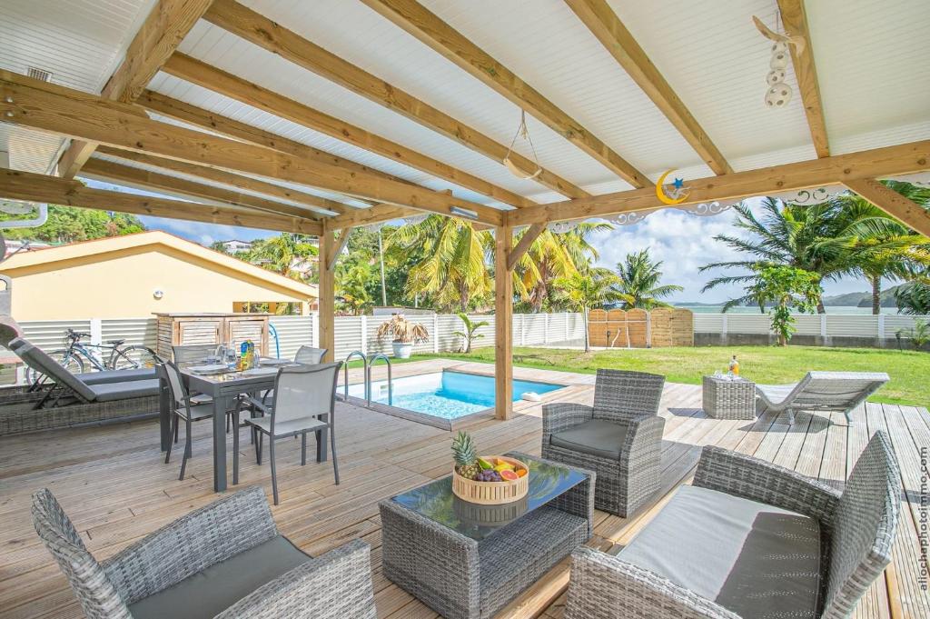 une terrasse avec une table, des chaises et une piscine dans l'établissement Villa belle lune, à La Trinité