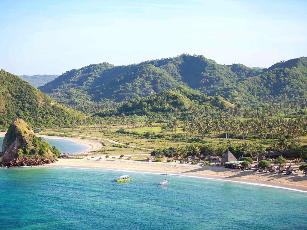 two boats in the water next to a beach at Novotel Lombok Resort & Villas in Kuta Lombok