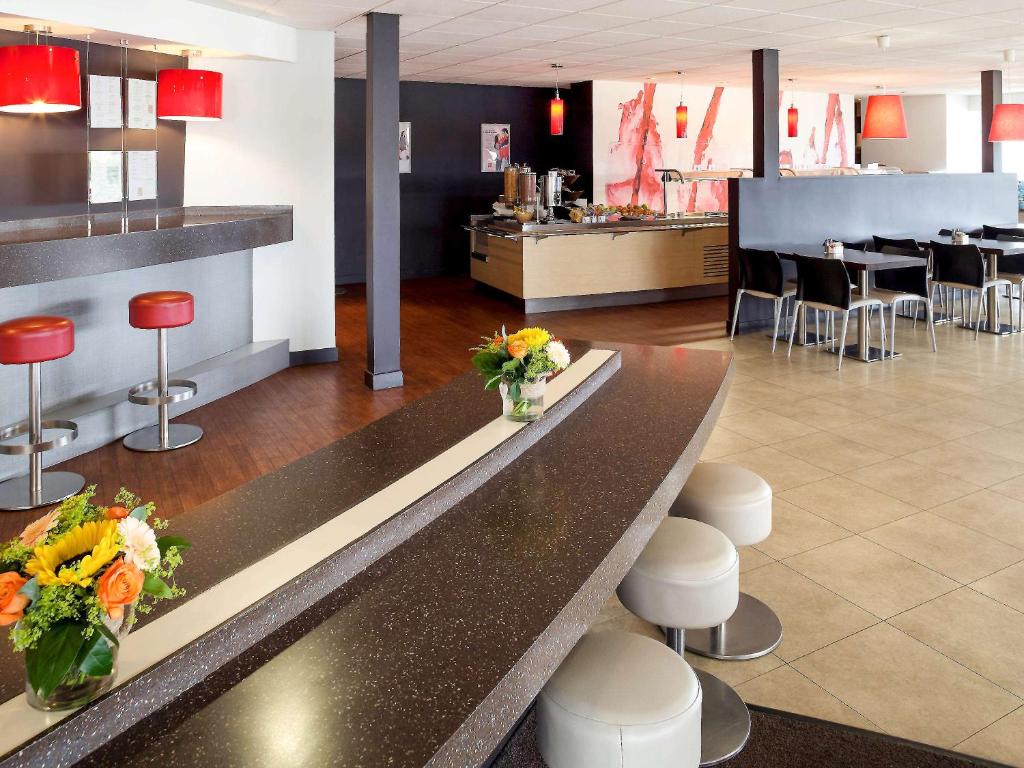 a lobby with a counter with flowers and stools at Ibis Hotel Dublin in Clondalkin