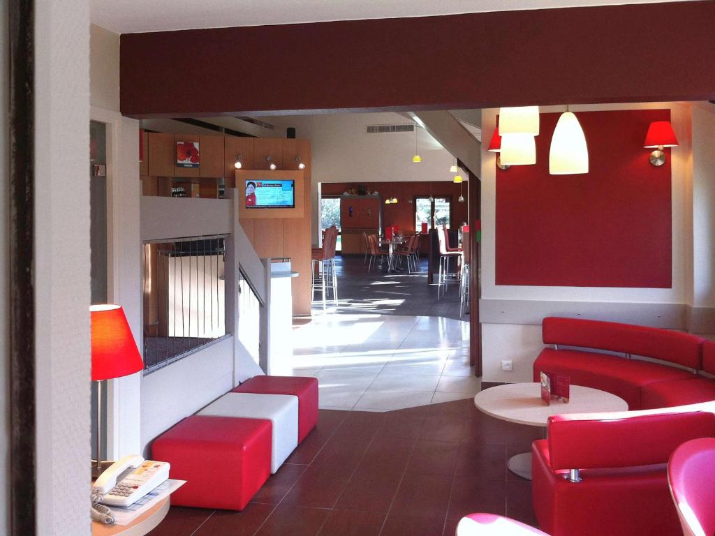 a red room with a red couch and red chairs at ibis Bourg en Bresse in Bourg-en-Bresse