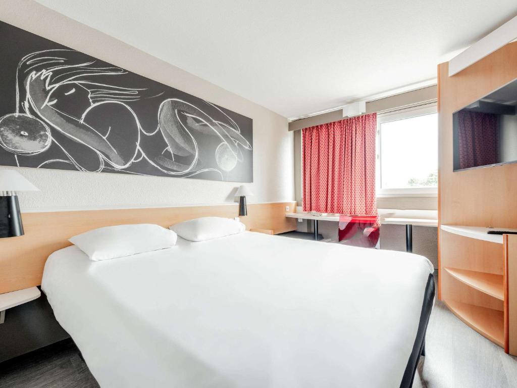 ein Schlafzimmer mit einem großen weißen Bett und einem Fenster in der Unterkunft ibis Toulouse Université in Toulouse
