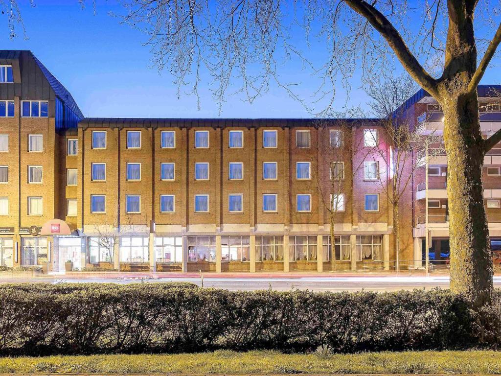 een groot gebouw met een boom ervoor bij ibis Paderborn City in Paderborn