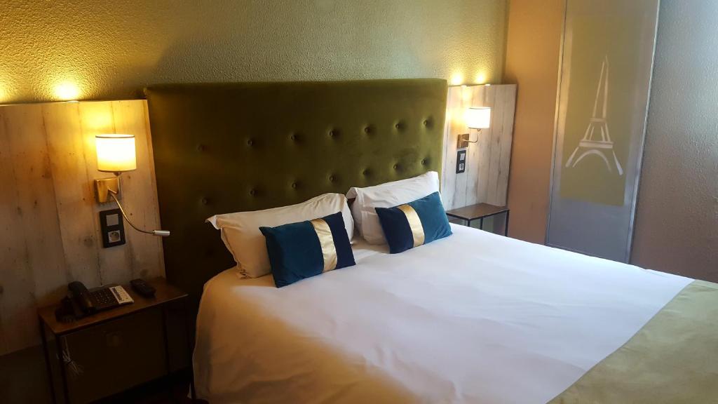 sypialnia z dużym białym łóżkiem z białymi i niebieskimi poduszkami w obiekcie Euro Hôtel Paris Créteil w mieście Créteil