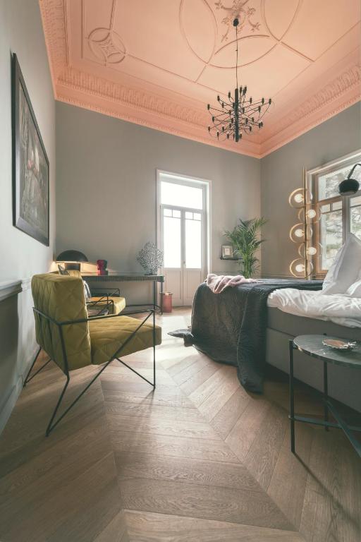 a bedroom with a bed and a chair and a chandelier at Aristide Hotel - Small Luxury Hotels of the World in Ermoupoli