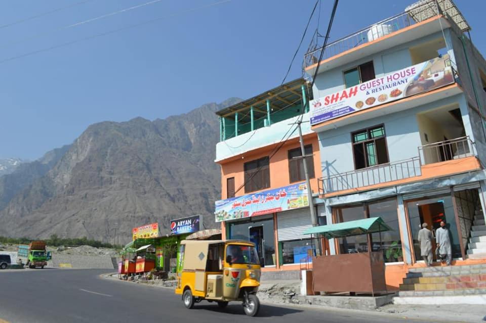 a small yellow car driving down a street in front of a building at Shah Guest House in Gilgit