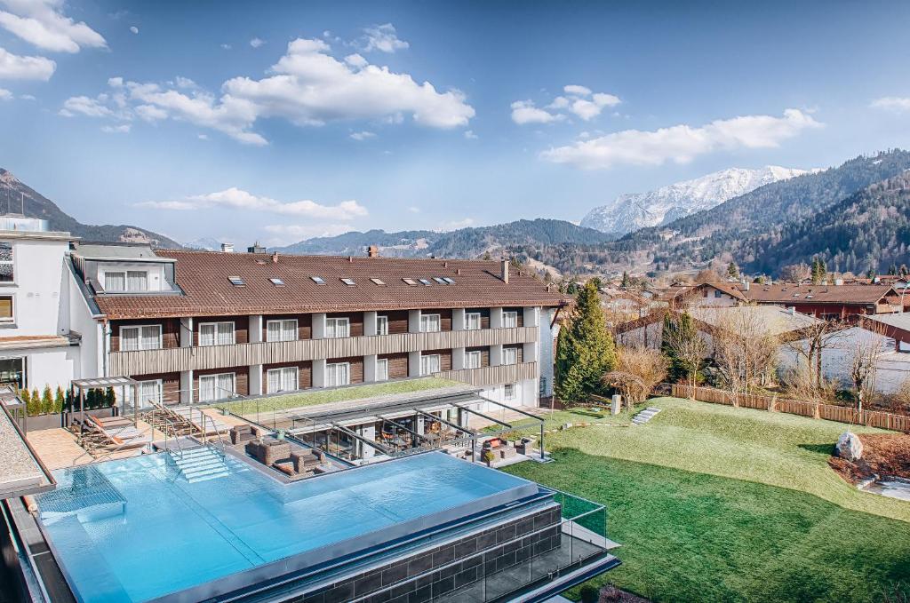 a building with a swimming pool next to a yard at Obermühle 4*S Boutique Resort in Garmisch-Partenkirchen