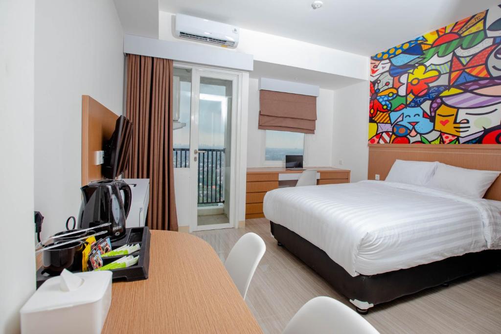 a bedroom with a bed and a desk with a tv at Urban Express HomTel - Serpong in Banten