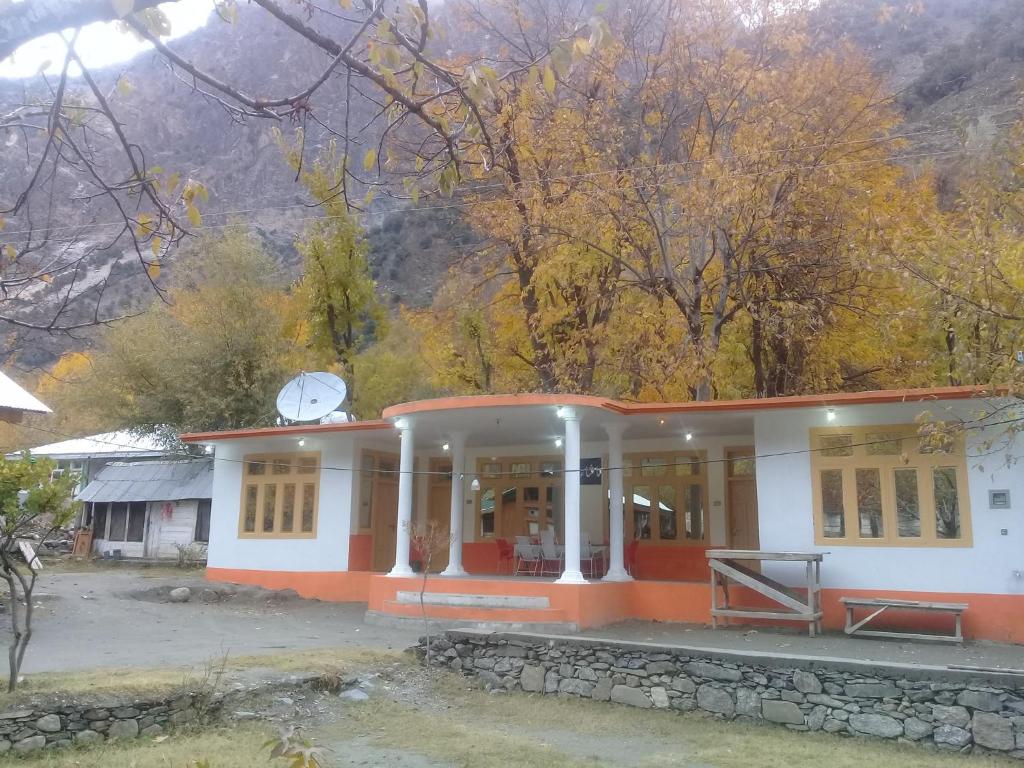 an orange and white building with a mountain in the background at Benazir Hotel Kalash 