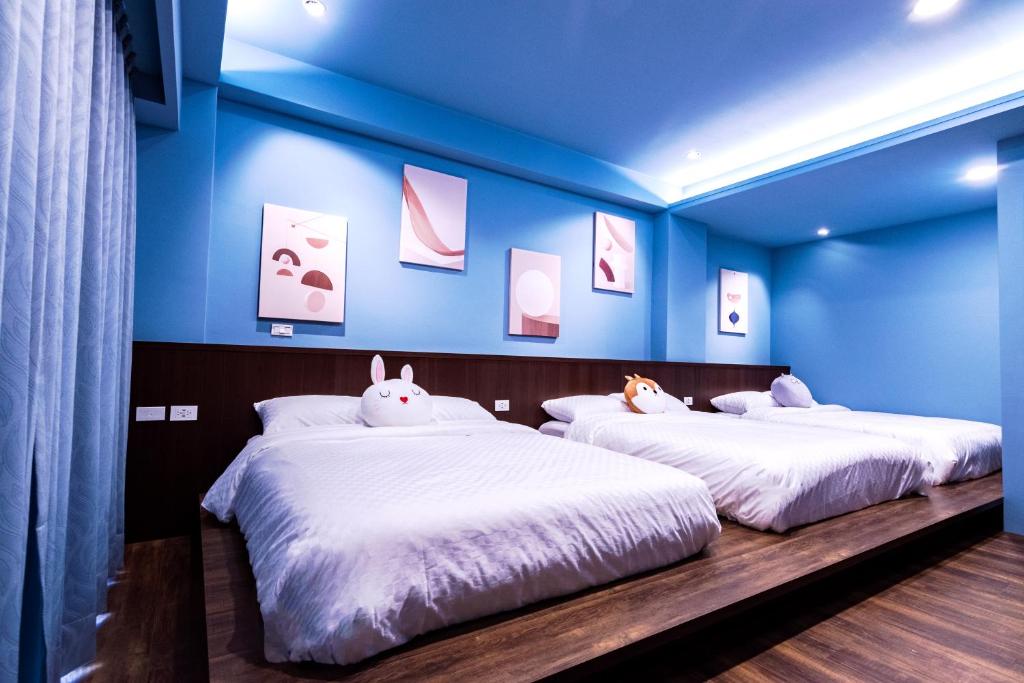 two beds in a room with blue walls at 幾何拼圖民宿 in Magong