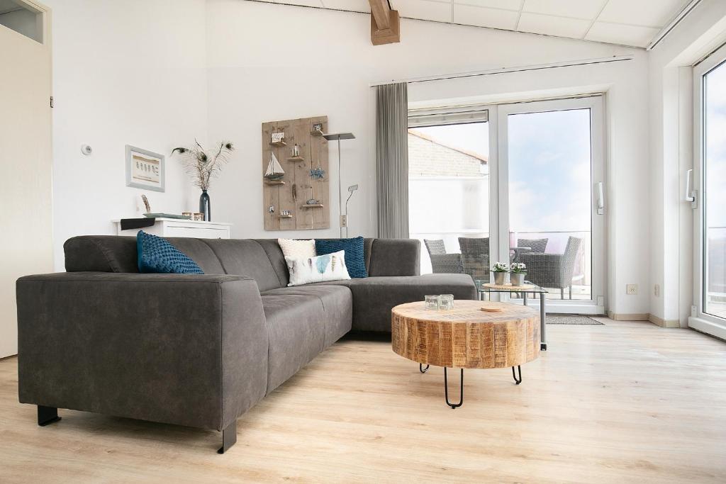 een woonkamer met een grijze bank en een tafel bij Strandappartement Duynblick in Julianadorp