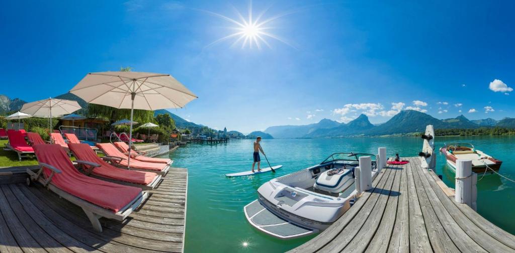 a person is standing on a paddle board on a dock at Hotel Furian in St. Wolfgang