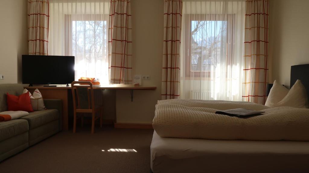 a bedroom with a bed and a couch and windows at Hotel Garni Löwen in Silz