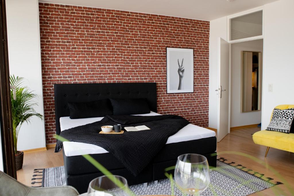 a bedroom with a bed and a brick wall at Tolles Apartment mit Weitblick über Augsburg in Augsburg