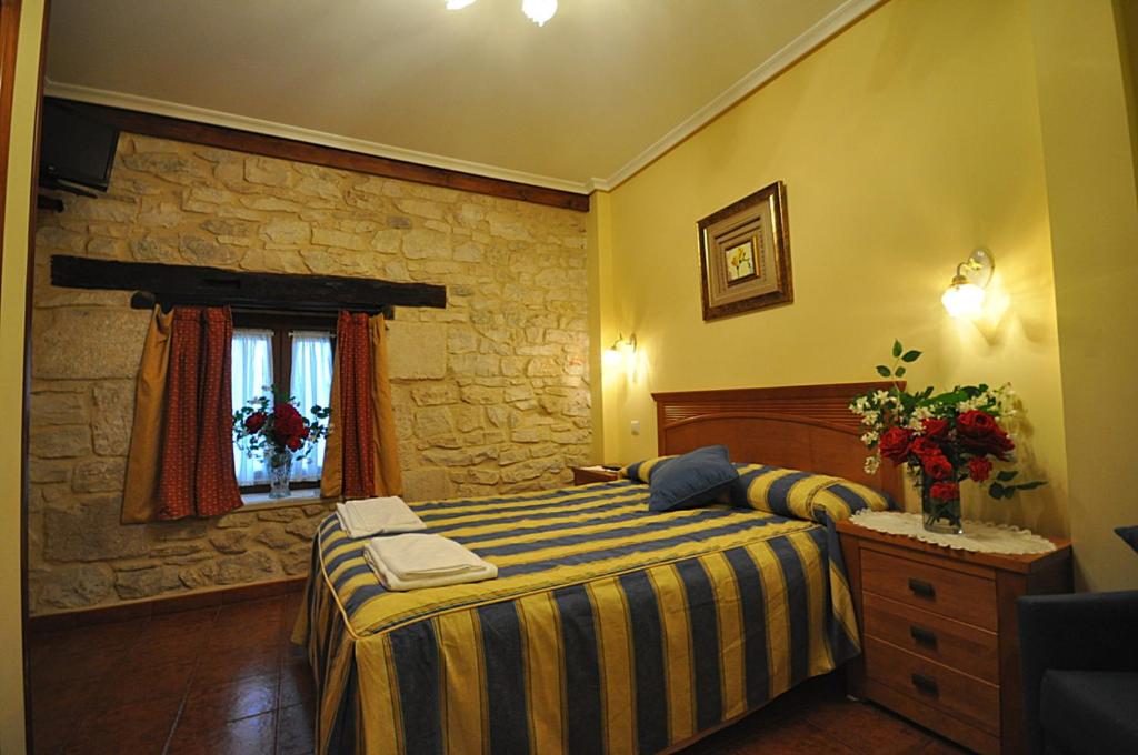 1 dormitorio con cama y pared de piedra en hotel rural anamari en Cigüenza