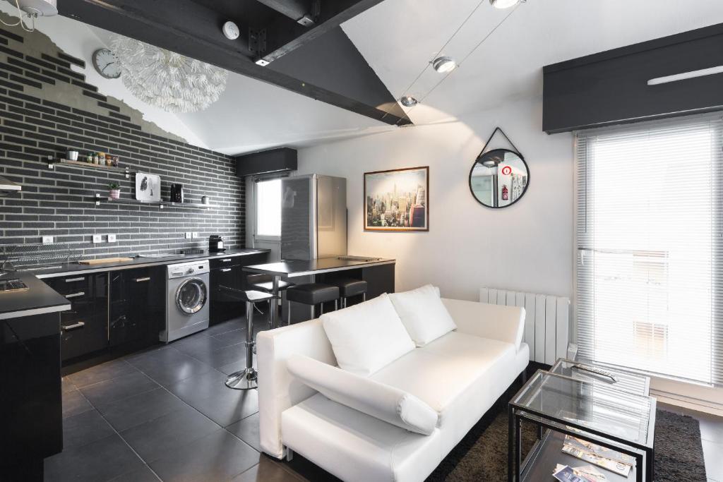 a living room with a white couch and a kitchen at L'Orchestre in Nantes